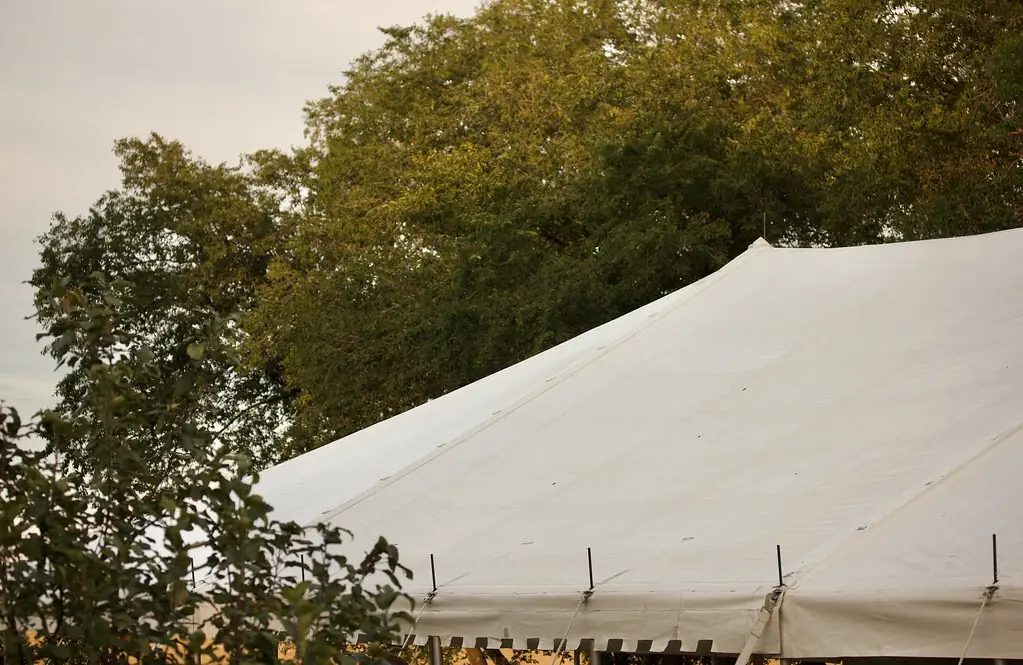 White tent roof among green trees, seen from above